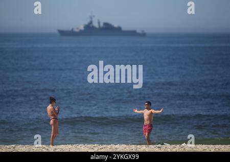 18. November 2024, Rio de Janeiro, Rio de Janeiro, Brasilien: Eine Frau macht ein Foto ihres Partners am Ipanema Beach vor einer brasilianischen Marinefregatte UniÃ - F 45. Am ersten Tag des G20-Gipfels 2024 ist die Polizei und das Militär in Rio stark präsent, da sich am 18. Und 19. November weltweit führende Politiker wie US-Präsident Joe Biden und der chinesische Präsident Xi Jinping in Rio de Janeiro treffen werden. Dies ist das erste Mal, dass Brasilien den Gipfel ausrichtet, auf dem die Staatschefs wichtige internationale Fragen erörtern werden. Die G20, die 85 % des globalen BIP und zwei Drittel der Weltbevölkerung repräsentieren, sind unter t Stockfoto
