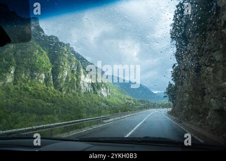 Eine nasse Straße an einem bewölkten und regnerischen Tag aus dem Inneren eines Fahrzeugs. Konzept des Fahrens, des Transports und der Vorsicht auf der Straße Stockfoto
