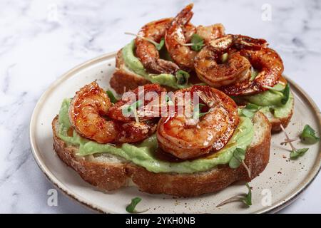 Sandwiches mit Avocado und karamelisierten Garnelen, Micro-Greens, Frühstück, auf einem Teller, Blick von oben, hausgemacht, keine Leute Stockfoto