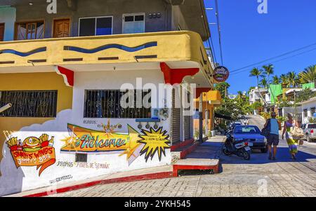 Puerto Escondido Oaxaca Mexiko 15. Februar 2023 typische schöne bunte Touristenstraße und Bürgersteig mit Stadtleben Autos Verkehrsgebäude heiß Stockfoto