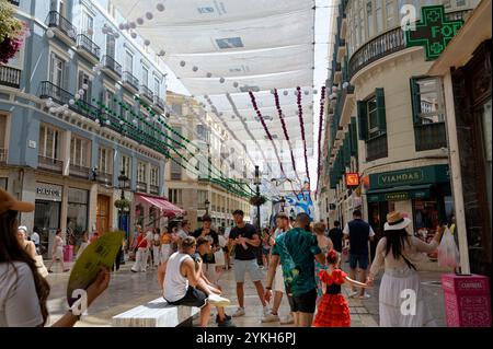 Die dekorierte Calle Larios wird während der August-Messe mit festlichen Besuchern und andalusischem Flair zum Leben erweckt Stockfoto