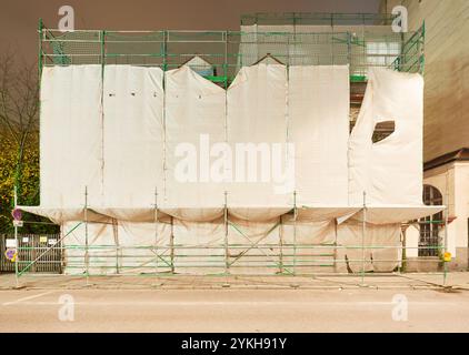 Abgehängte Fasade eines Hauses währned der Renovierung bei Nacht aufgenommen Stockfoto