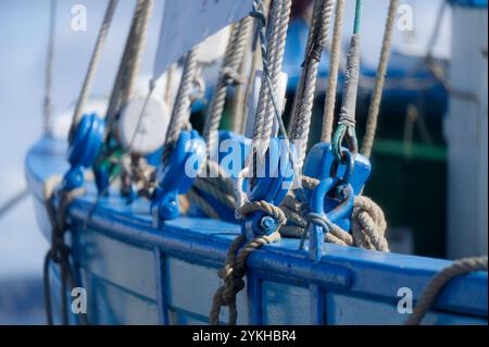Ein detaillierter Blick auf Seile und blaue Seilrollen auf einem traditionellen hölzernen Segelboot Stockfoto