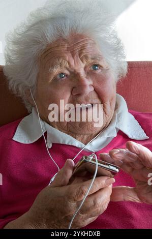 ÄLTERE DAME iPod MEDIEN AUDIO BUCH MUSIK PLAYER LERNEN SPRACHE OHRHÖRER ältere Dame mit ihrer neuen Technologie tragbare Player für eine Vielzahl von digitalen Audio-Medien-Dateien Stockfoto