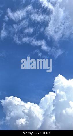 Weiße Wolken schweben am hellblauen Himmel. Diese Wolken verleihen der Szene einen dramatischen Effekt und erzeugen einen fesselnden Kontrast zwischen weiß und Blau. Stockfoto