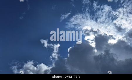 Sonnenlicht, das hinter dunklen Wolken am blauen Himmel auftaucht. Dieser Lichteffekt verleiht der Szene eine dramatische und magische Note und zeigt die Kraft. Stockfoto