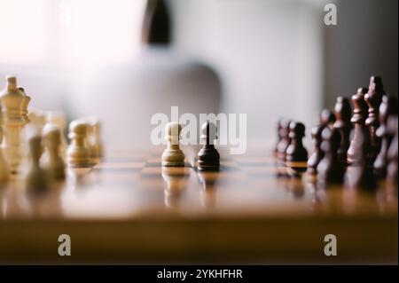 Ein Schachbrett mit einer weißen und einer schwarzen Schachfigur darauf. Der schwarze Bauer befindet sich in der Mitte des Bretts und ist von anderen Teilen umgeben. Das Brett ist aus Holz und hat ein kariertes Muster Stockfoto