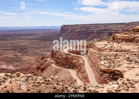 Wunderschöner Panoramablick auf die gewundene und steile Moki Dugway Road in Utah, USA. Die Landschaft zeigt rote Felsformationen und ein Auto, das die Straße überquert. Stockfoto