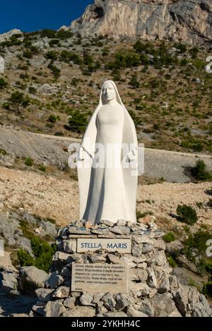 Statue der Jungfrau Maria in den kroatischen Bergen, mit einer Gebetstafel „Heil Maria“ umgeben von der Natur. Stockfoto