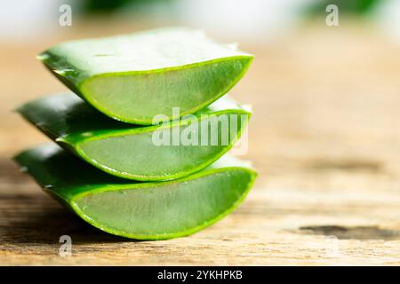 Sie können auf dem Bild Blätter der Aloe Vera Pflanze und kleine Stücke ihres Zellstoffes auf einem hölzernen Hintergrund sehen Stockfoto