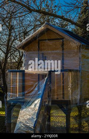 Ein hölzernes Baumhaus für Kinder, geschützt gegen Winterschnee und Regen mit Folienattraktionen für Kinder, spielen mit Kindern, Spielhaus Stockfoto