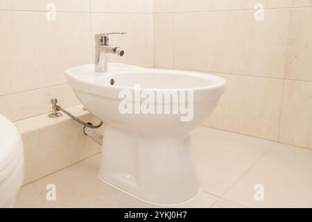 Weißes Bidet im Badezimmer, beige Fliesen. Ruhiges Luxuskonzept Stockfoto