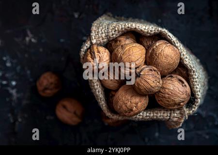 Muttern. Walnusskerne und ganze Walnüsse auf dunklem Steintisch. Schwarzer Hintergrund. Stockfoto