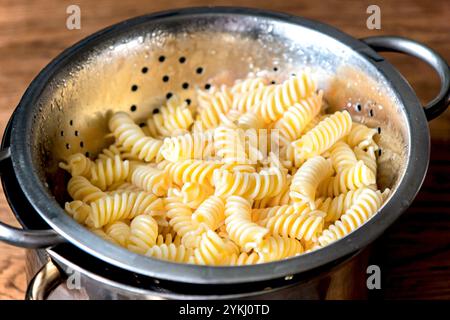 Fusilli Nudeln in einem Edelstahlsieb auf Hintergrund Stockfoto