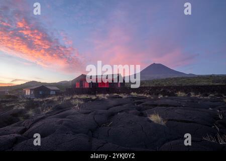 Cabrito auf der Insel Pico auf den Azoren hat einen Badebereich aus schwarzer Lava mit traditionellen Lavasteinhäusern mit Blick auf den majestätischen Mount Pico. Stockfoto