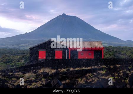 Cabrito auf der Insel Pico auf den Azoren hat einen Badebereich aus schwarzer Lava mit traditionellen Lavasteinhäusern mit Blick auf den majestätischen Mount Pico. Stockfoto