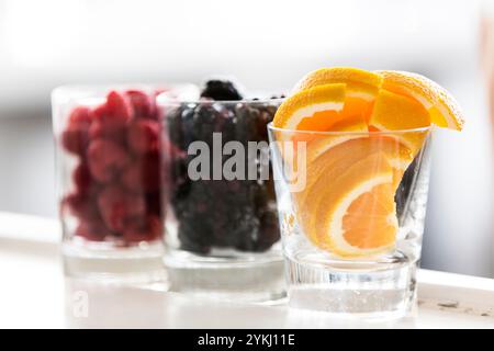 Frische Beeren und Orangenscheiben in Glasbechern Stockfoto