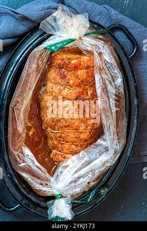 Ein großes Stück Schweinefleisch in Gewürzen gebacken und mit Fäden umwickelt. Stockfoto