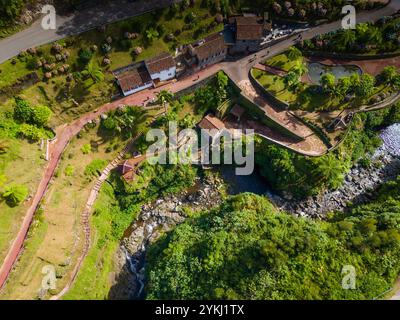 Ribeira dos Caldeiroes. Drohnenblick auf die kleine Stadt neben Cascata da Ribeira dos Caldeiroes.in Sao Miguel, Azoren Berge Stockfoto