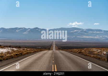 U.S. Route 50, die einsamste Straße der USA, aus der Vogelperspektive in Richtung schneebedeckter Berge. Leere Straße und klarer blauer Himmel. Stockfoto