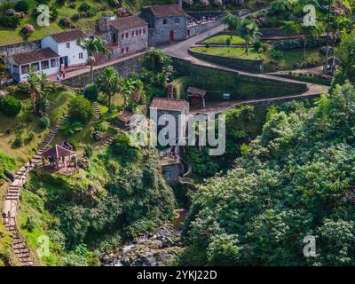 Ribeira dos Caldeiroes. Drohnenblick auf die kleine Stadt neben Cascata da Ribeira dos Caldeiroes.in Sao Miguel, Azoren Berge Stockfoto