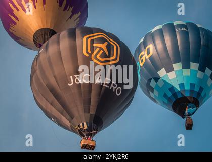 Farbenfrohe Heißluftballons, die während einer lebhaften Ballonfahrt am klaren blauen Himmel schweben und Abenteuer, Freiheit und Outdoor-Freizeitaktivitäten zeigen Stockfoto
