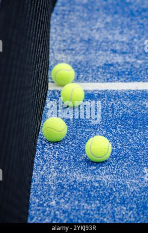 Vier Bälle in der Nähe des Netzes auf einem blauen Paddle-Tennisplatz, Hintergrund für Schlägersportarten Stockfoto