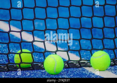 Drei Bälle in der Nähe des Netzes, ein blauer Paddle-Tennisplatz, Hintergrund für das Tenniskonzept Stockfoto