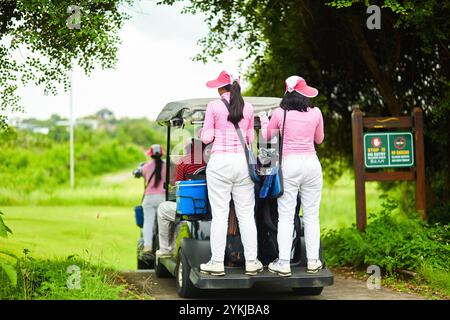 Frauen, die auf Golfwagen stehen, während sie sich bewegen. Bali, Indonesien - 03.24.2018 Stockfoto