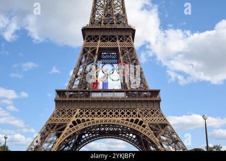 Paris, Frankreich - August 2024 in Paris fanden in diesem Jahr die Olympischen Spiele statt, und das olympische Symbol der Ringe hängt mit der französischen Flagge auf dem Eiffelturm Stockfoto