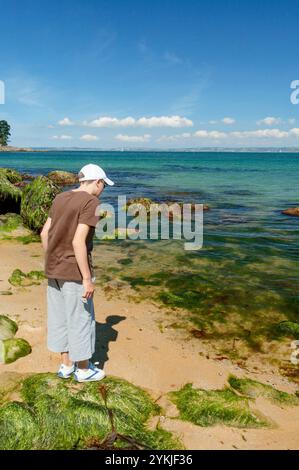 Ein kleiner Junge sucht an der felsigen Küste in der Bretagne, Frankreich, nach Kochsalzlösung Stockfoto