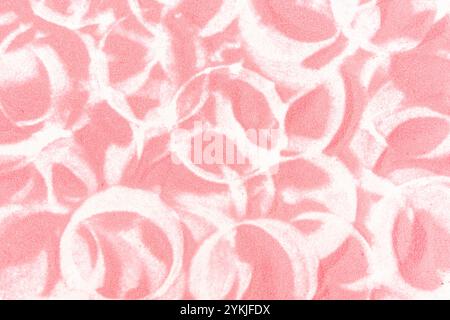 Rosafarbener Sand mit kreisförmigen Spuren auf weißem Papierhintergrund. Stockfoto