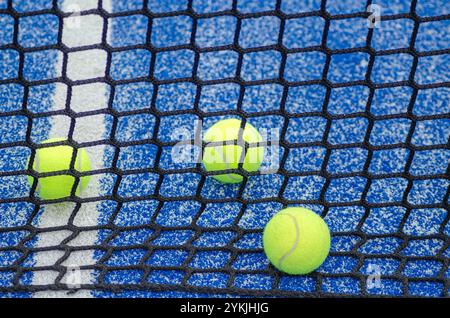 Drei Paddeltennisbälle hinter dem Netz eines Paddeltennisplatzes, Hintergrund für das Konzept des Racketsports Stockfoto