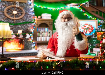 In seiner rustikalen Blockhütte liest der Weihnachtsmann die Wunschliste eines hoffnungsvollen Kindes. Die traditionelle Weihnachtsszene unterstreicht seine Rolle bei der Weihnachtsfreude und Weihnachtsgeschenke für Kinder auf der ganzen Welt. Stockfoto