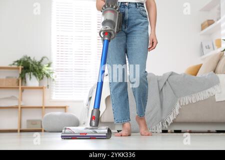 Frau, die den Boden mit schnurlosem Staubsauger in Innenräumen reinigt, Nahaufnahme Stockfoto