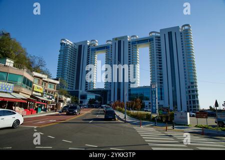 Sokcho, Südkorea - 3. November 2024: Blick auf das hoch aufragende Cassia Sokcho Hotel in der Nähe von Daepo Port, im Kontrast zu den nahe gelegenen traditionellen Geschäften und Lo Stockfoto