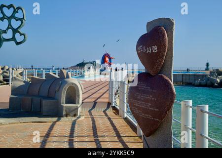 Sokcho, Südkorea - 3. November 2024: Herzförmige und abstrakte Skulpturen zieren den Wellenbrecher am nördlichen Ende des Sokcho Beach mit Jodo Islan Stockfoto