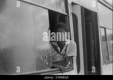 Der junge kubanische Junge reitet von der Schule nach Hause und blickt aus dem Fenster eines Busses. Stockfoto