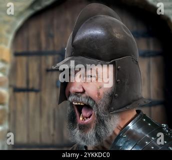 Ein Mann in mittelalterlicher Rüstung ruft vor einem Burgtor Stockfoto