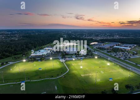 Leute spielen bei Sonnenuntergang im beleuchteten öffentlichen Stadion Fußball. Aktives Lebenskonzept Stockfoto