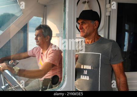 Para, Brasilien. November 2023. Amarildo Souza Santos (rechts) ist Co-Direktor der Z20-fischereiunion in Santarem, Brasilien. Er bringt das Boot nach Hause. Seine isolierte Gemeinde Santa Maria do Tapara ist nur mit dem Boot erreichbar. Zwischen September und November 2023 erlebte das Amazonasgebiet eine beispiellose Dürre. Brände, die Flora und Fauna verwüsteten, und viele Gemeinden waren vom Rest der Welt abgeschnitten, denn für ihre Navigation sind sie auf ausgetrocknete Wasserstraßen angewiesen. (Credit Image: © Apolline Guillerot-Malick/SOPA Images via ZUMA Press Wire) NUR REDAKTIONELLE VERWENDUNG! Nicht für kommerzielle ZWECKE! Stockfoto