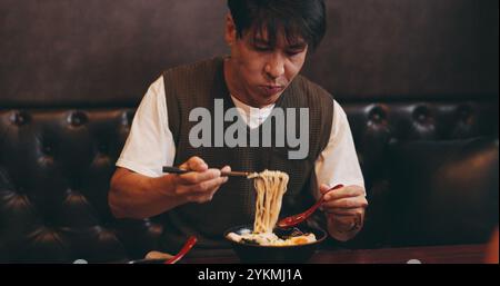 Japanischer Mann, essen Mittagessen und hungrig im Restaurant für Ernährung, Kultur und gesunde Mahlzeit. Männliche Person, Gastfreundschaft und Diät mit traditionellen Stockfoto