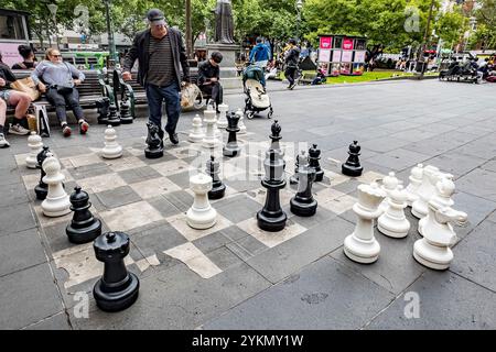 Die Menschen spielen eine Partie Schach mit übergroßen Spielern auf einem großen Brett in einem belebten Stadtpark Stockfoto