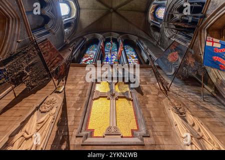 Der Chor der St. Patrick's Cathedral in Dublin verfügt über ein großes Mosaikkreuz, flankiert von Militärflaggen und Steinschnitzereien. Oben, los geht's. Stockfoto