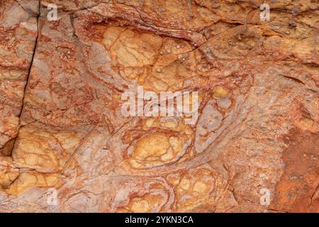 Detaillierte Textur des Basaltgesteins vom Giant's Causeway mit rötlichen Mustern, die durch vulkanische Aktivität und langfristige eisenreiche Verwitterung entstanden sind Stockfoto