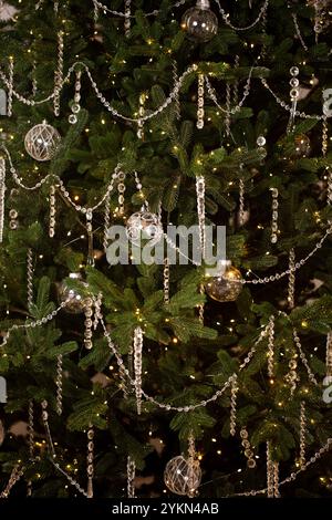 Ein Weihnachtsbaum mit vielen Ornamenten und Lichtern. Der Baum ist beleuchtet und die Lichter leuchten hell Stockfoto