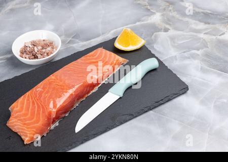 Filet von rohen Lachsfischen mit Zitrone und einem Messer auf dem Schneidebrett. Draufsicht. Stockfoto