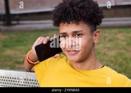 Lächelnder latein-Teenager-Mann, der auf dem Handy spricht Stockfoto
