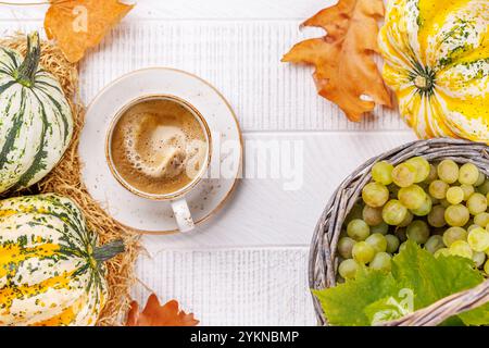 Speisen im Herbst-Stil mit Kaffee, Kürbissen, Trauben und Herbstblättern auf einem Tisch für eine gemütliche, saisonale Atmosphäre. Enthält Kopierraum f Stockfoto