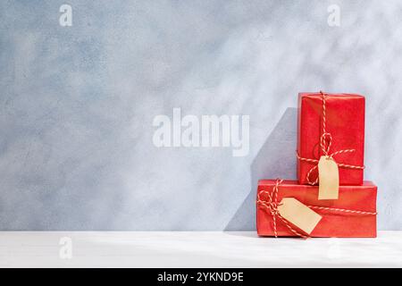 Weihnachtsschablone mit Geschenkboxen auf einem Tisch mit Schatten und Sonnenstrahlen, die sanft an die Wand fallen und eine festliche Winteratmosphäre schaffen Stockfoto